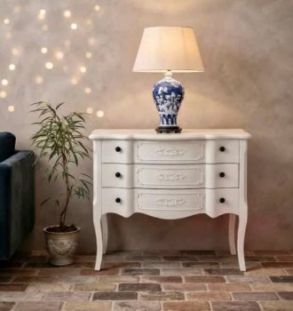 Cómoda blanca con lámpara: Cómoda blanca de tres cajones con patas curvas y lámpara de cerámica azul y blanca.