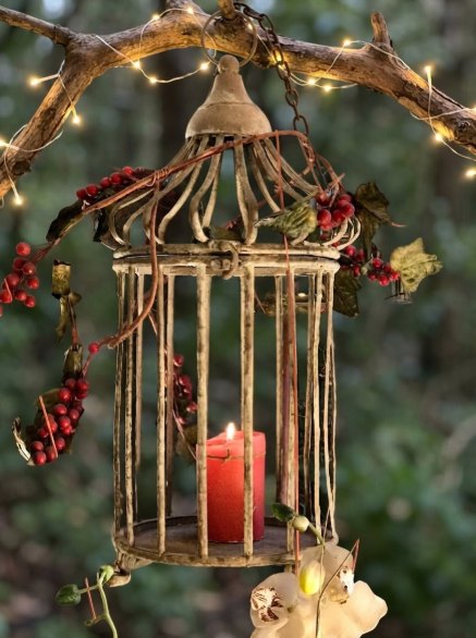 Jaula decorativa con vela: Jaula de metal envejecido con vela roja, ideal para colgar en interior o jardín.