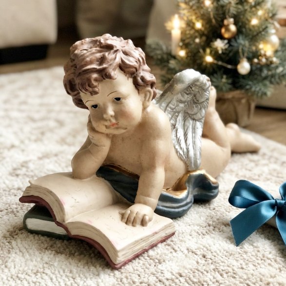 Angelito leyendo: Figura de angelito recostado leyendo un libro, con alas plateadas.