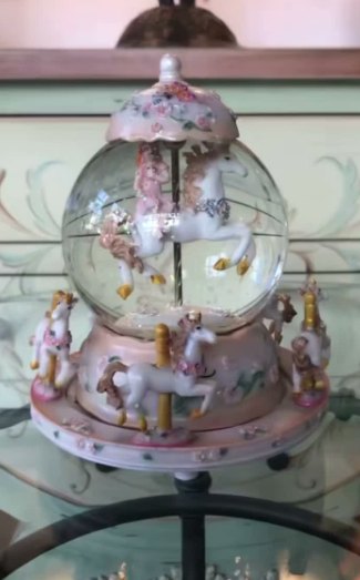 Globo con carrusel rosa: Globo de cristal con carrusel de caballos blancos y detalles florales en rosa.