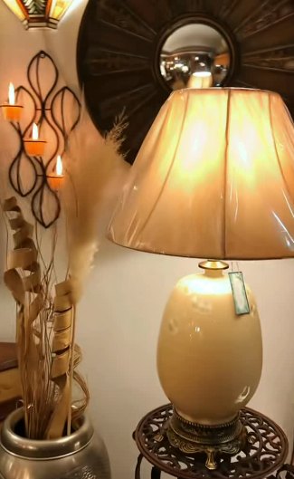 Lámpara de mesa beige: Lámpara de mesa con base de cerámica beige y pantalla, sobre mesa de hierro calado.