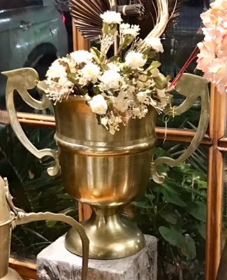 Copa dorada con flores secas: Copa decorativa de metal dorado con asas, ideal con arreglos de flores secas.